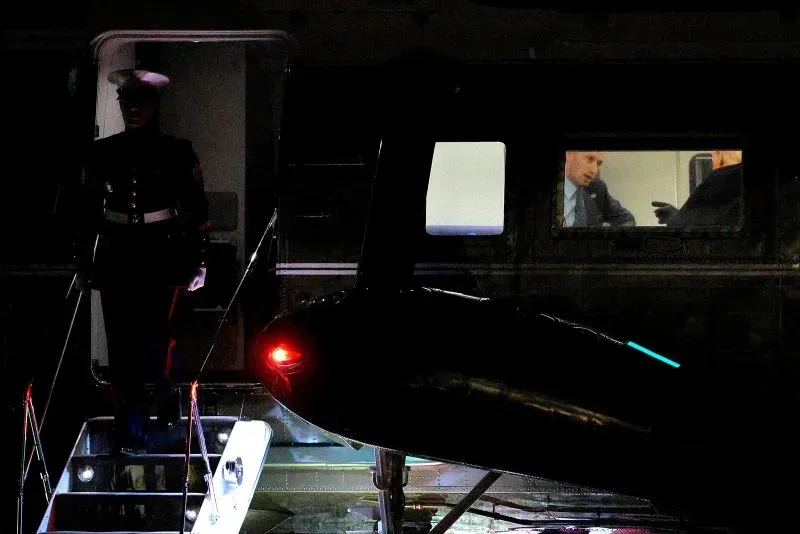 ستيفن ميلر، مستشار ترامب، يظهر داخل طائرة هليكوبتر بينما يقف حارس في الخلفية، مما يعكس دوره البارز في الإدارة.