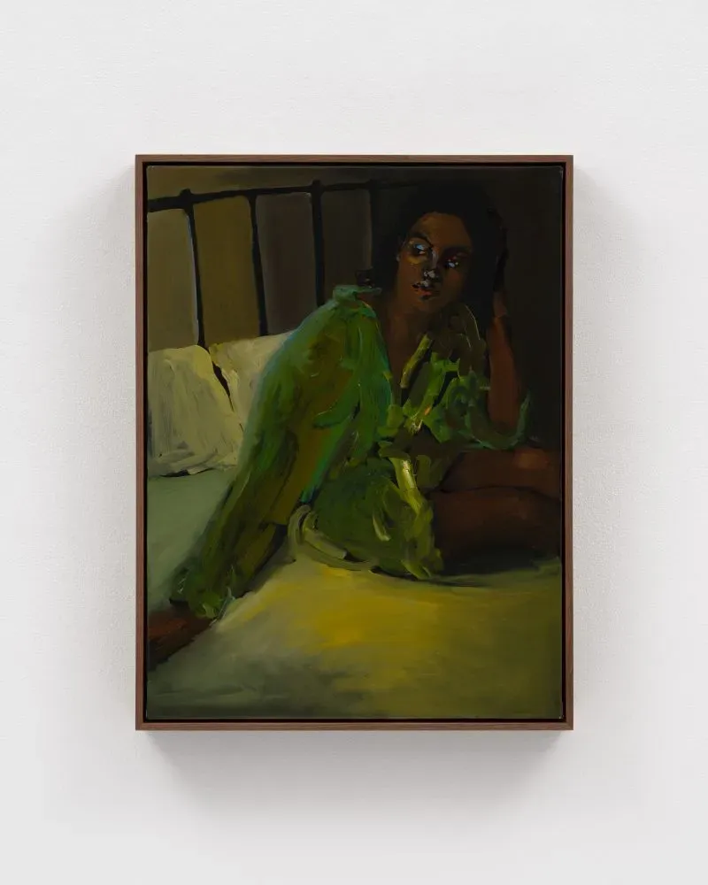 امرأة ترتدي قميصًا أخضر تسترخي على السرير، تعكس لحظة من العزلة والراحة، مستوحاة من أعمال الفنانة دانييل ماكيني.