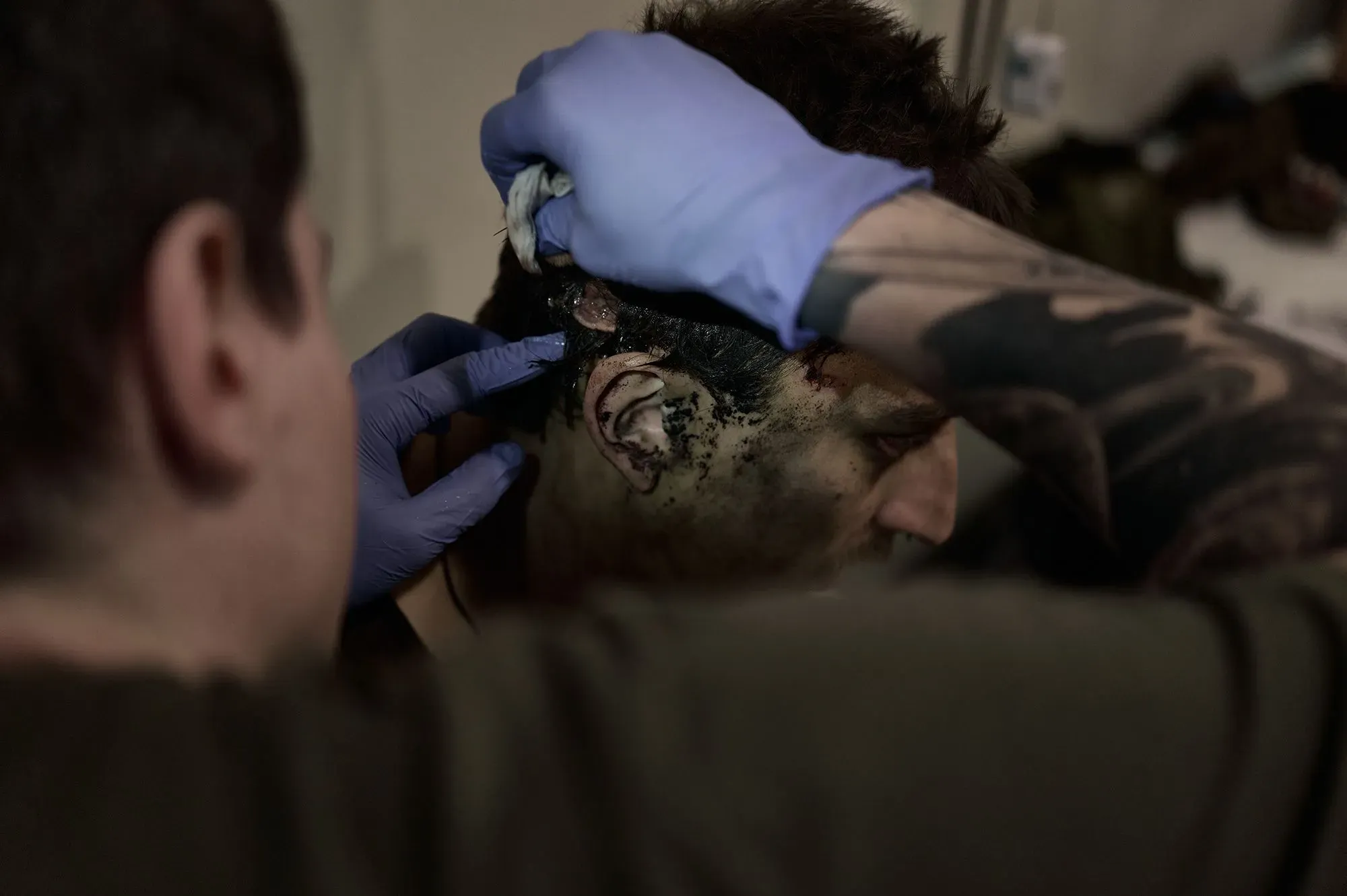 مسعف أوكراني يعالج جرحى في منطقة بوكروفسك، حيث تظهر آثار الإصابات والدم، مما يعكس الأوضاع الصعبة في الحرب.