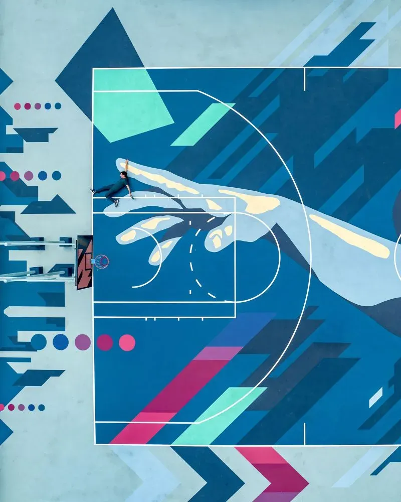 ملعب كرة سلة ملون بتصميم هندسي معقد، يظهر شخصًا يتدرب، محاطًا بألوان زاهية تعكس تصميمات حضرية فريدة في هونغ كونغ.