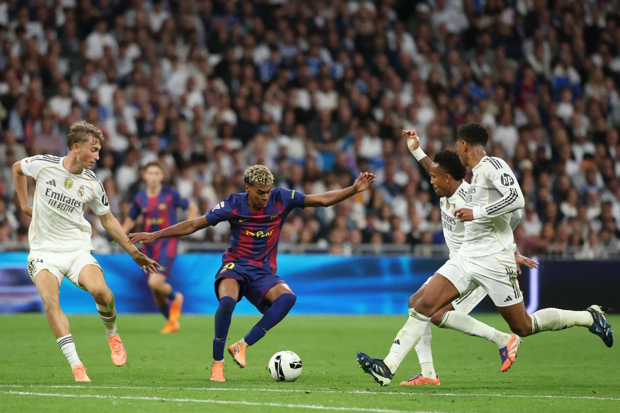 لاعب كرة قدم من برشلونة يحاول مراوغة ثلاثة لاعبين من ريال مدريد في مباراة كرة قدم حماسية ضمن منافسات الدوري الإسباني.