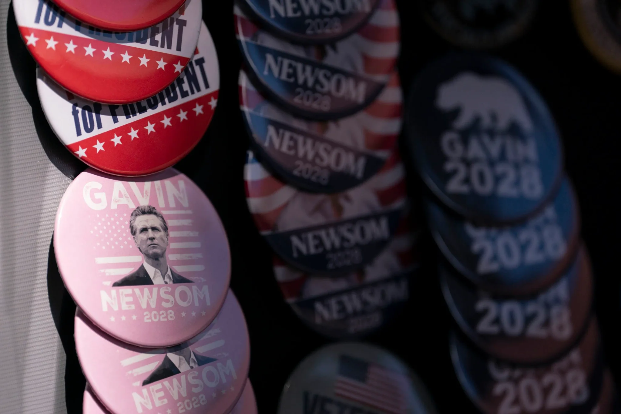 أزرار حملات انتخابية مكتوب عليها "Newsom 2028" و"Top President" تعكس استعدادات حاكم كاليفورنيا غافين نيوزوم للانتخابات الرئاسية 2028.