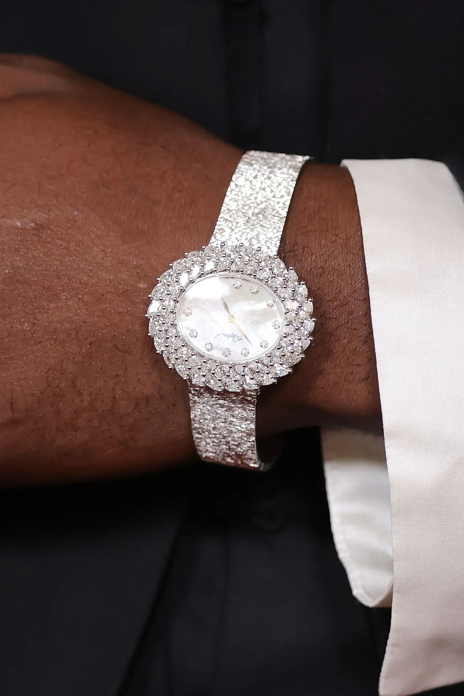 ساعة فاخرة ذات إطار فضي وميناء أبيض مزين بالألماس، تُرتدى على معصم شخص، تعكس شغف الجيل Z بعالم الساعات.