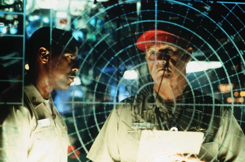 مشهد من فيلم يظهر ضابطين في غرفة التحكم البحرية، مع شاشة رادار في الخلفية، يعكسان أجواء التوتر في السينما الأمريكية.