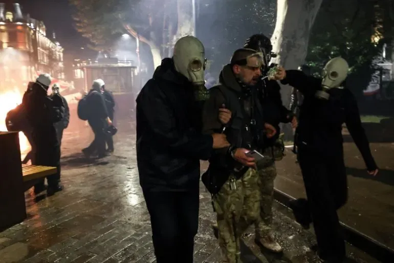 محتجون يرتدون أقنعة واقية من الغاز أثناء مواجهة مع الشرطة في تبليسي، وسط أجواء من التوتر بعد الانتخابات المحلية.