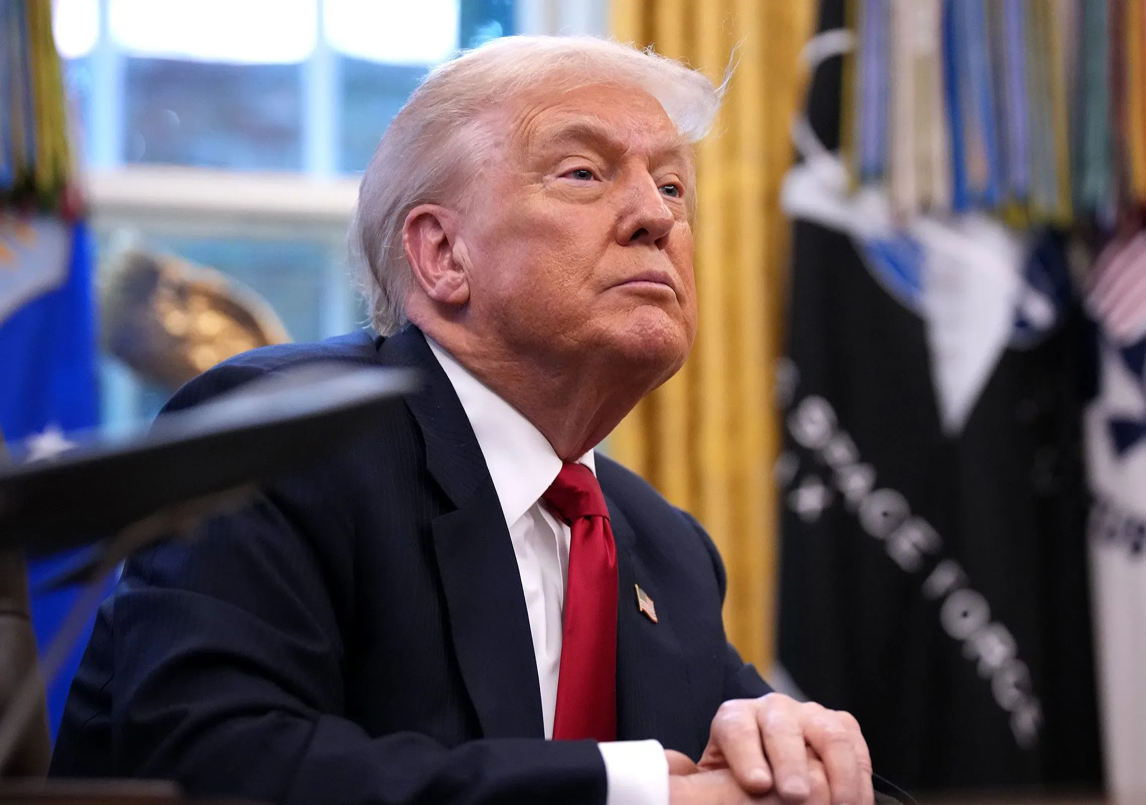 ترامب يجلس في المكتب البيضاوي، مع تعبير جاد، وسط تفاصيل مكتبية تشير إلى التوترات القانونية المتعلقة بقضية الانتخابات.