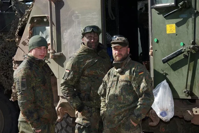 جنود ألمان يرتدون زيهم العسكري، يقفون أمام مركبة عسكرية، يعكسون الاستعدادات العسكرية المتزايدة في ألمانيا في ظل التوترات الجيوسياسية.