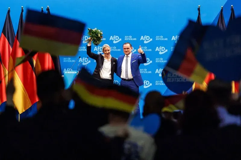 زعيم حزب البديل من أجل ألمانيا أليس فايدل تحتفل مع حشد من المؤيدين بعد نتائج الانتخابات، مع أعلام ألمانيا ترفرف في الخلفية.