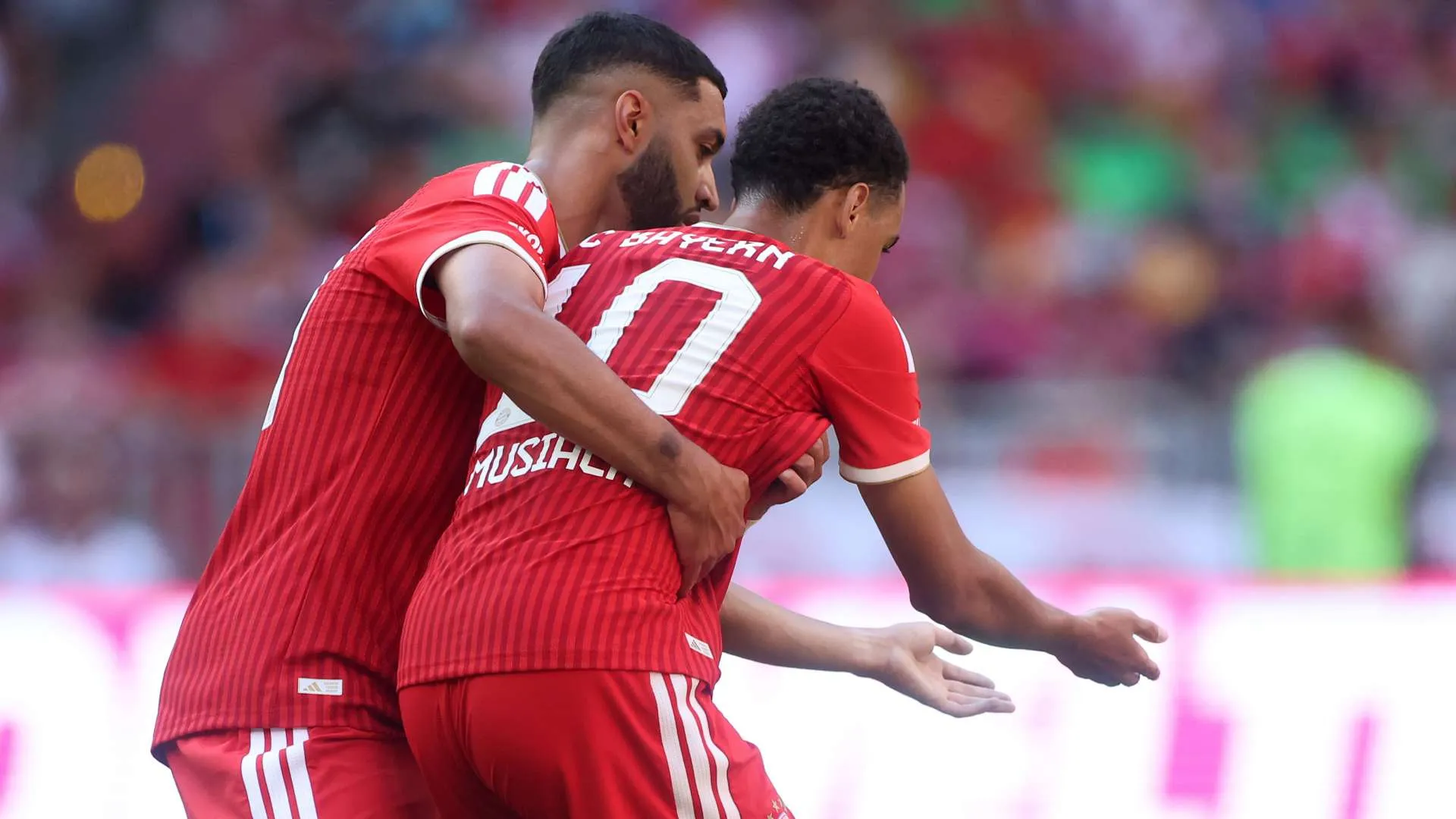 لاعبا بايرن ميونخ يحتفلان بهدف خلال مباراة، مع التركيز على جمال موسيالا في سياق تحدياته الصحية ونوبات الغياب العصبية.
