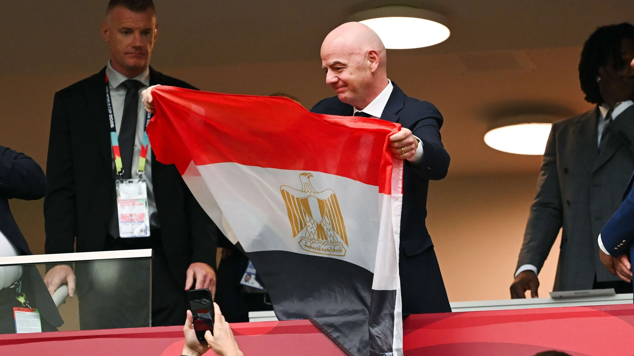 رئيس FIFA جياني إنفانتينو يحمل علم مصر خلال حدث رسمي، مع مناقشة توسع كأس العالم إلى 64 فريقاً وتأثيره على كرة القدم الدولية.