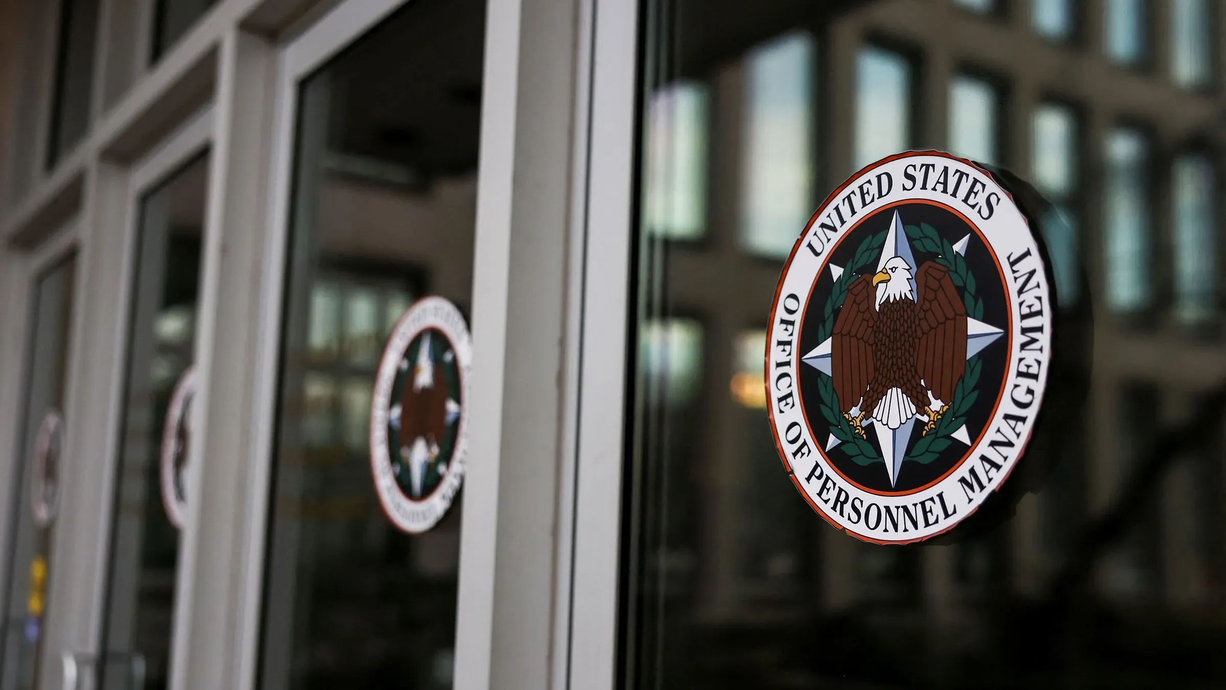 شعار مكتب إدارة شؤون الموظفين الأمريكي على زجاج المدخل، يرمز إلى إدارة التوظيف الفيدرالي والخصوصية.