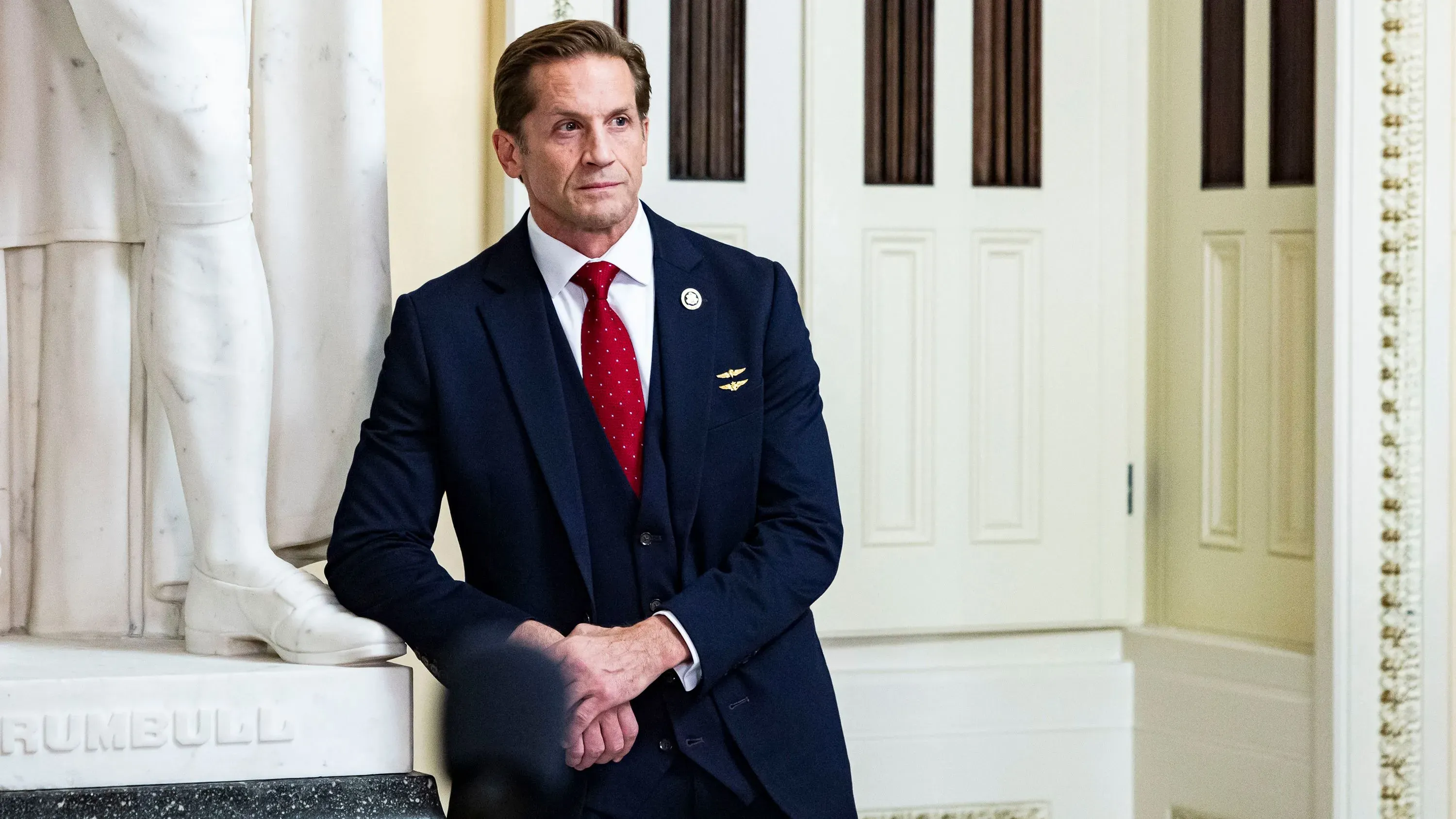 النائب الجمهوري ريتش ماكورميك يقف في قاعة المدينة في جورجيا، محاطًا بتمثال، أثناء رده على انتقادات الناخبين بشأن إدارة ترامب.