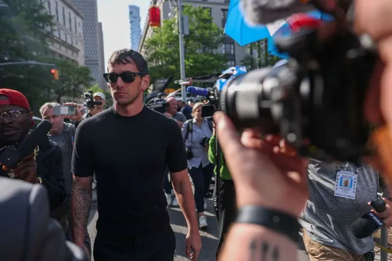 يظهر أليكس فاين وهو يسير وسط حشد من الصحفيين والمشجعين، مرتديًا نظارات شمسية وقميص أسود، في إطار دعم زوجته كاسي فينتورا خلال محاكمة تتعلق بالعنف الأسري.