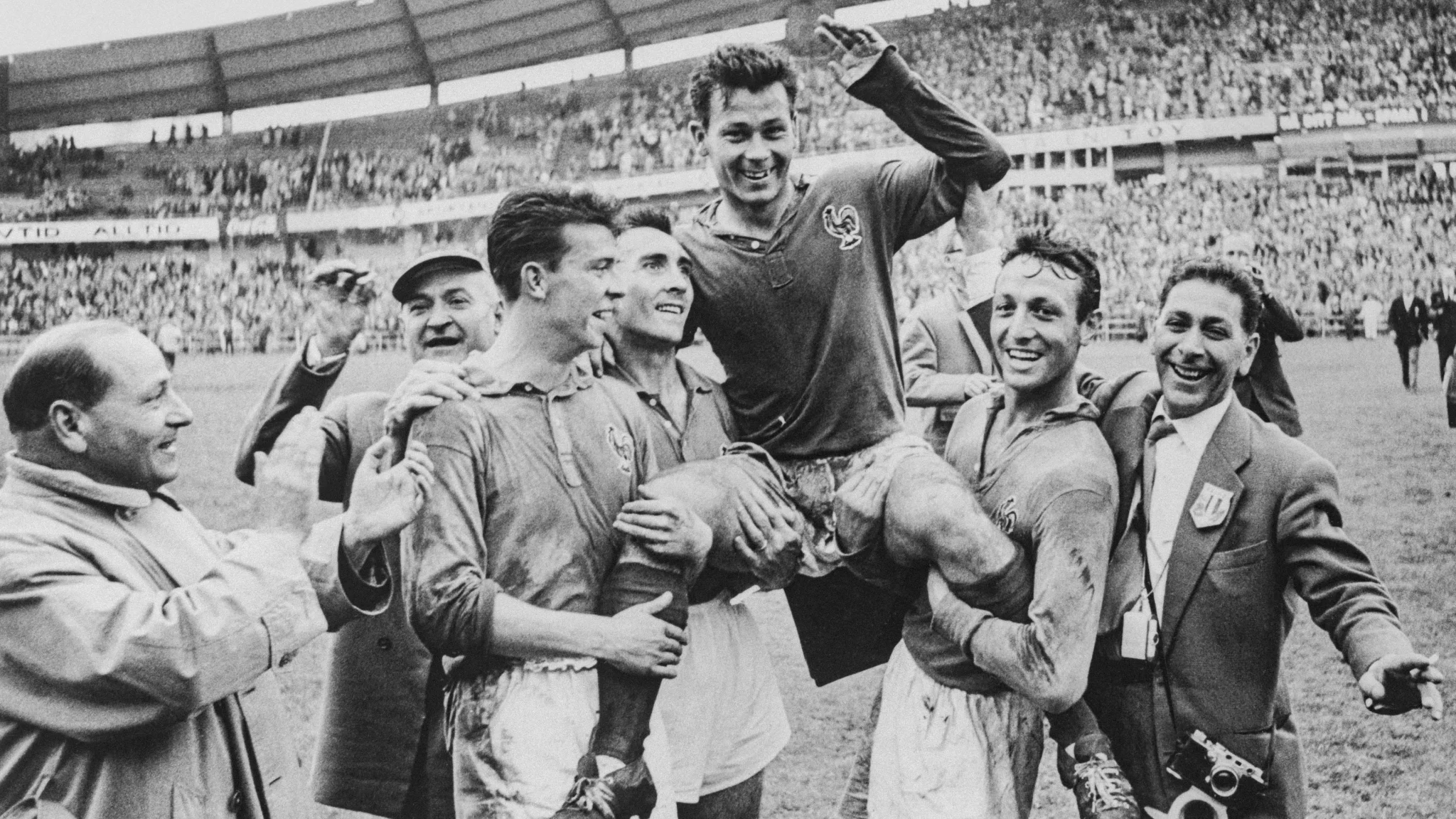 لاعبو منتخب فرنسا لكرة القدم يرفعون زميلهم احتفالاً بلقب كأس العالم 1958 وسط حشد جماهيري في الملعب، يعكس تاريخ وتألق الهجوم الفرنسي في المونديال.