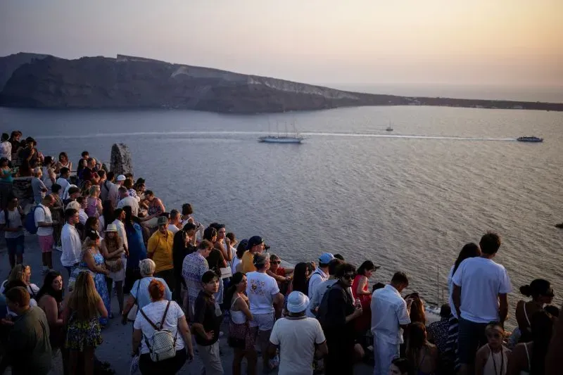حشود من السياح في سانتوريني يستمتعون بغروب الشمس على البحر، بينما تشهد الجزيرة نشاطًا زلزاليًا ملحوظًا.