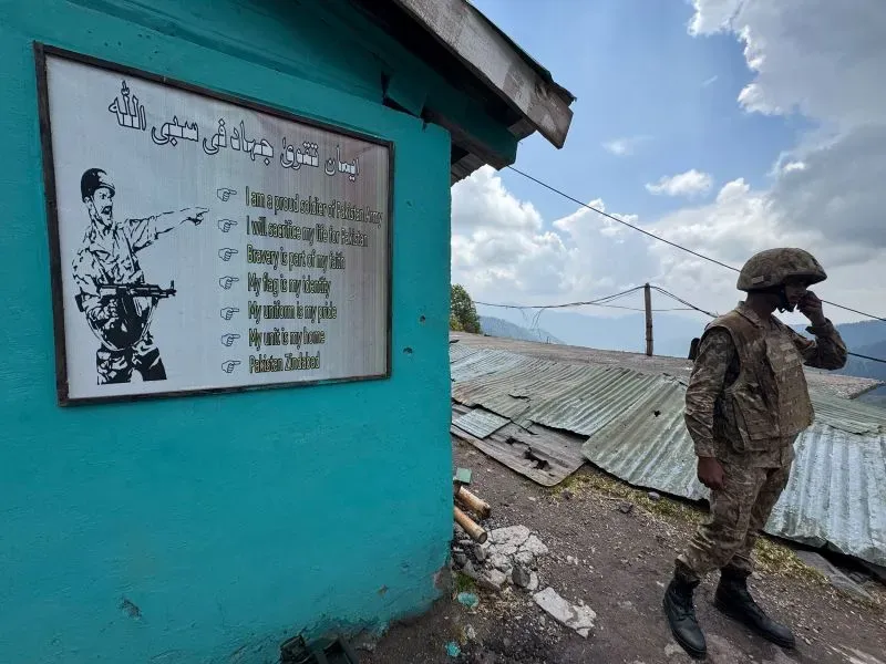 جندي باكستاني يقف بجانب لوحة تحمل عبارات تتعلق بالفخر الوطني، في منطقة جبلية متنازع عليها في كشمير.