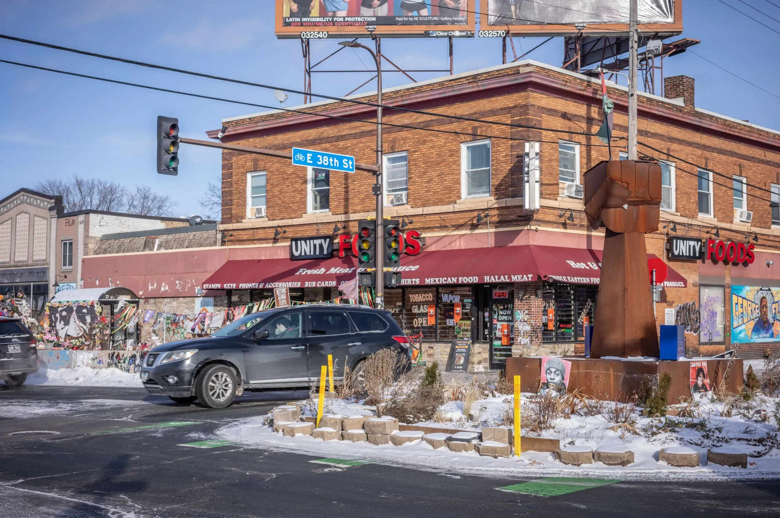 منطقة مينيابوليس حيث يظهر متجر "يونتي فودز" مع لافتات تذكارية، تعكس تأثير الأحداث المأساوية على المجتمع المحلي.