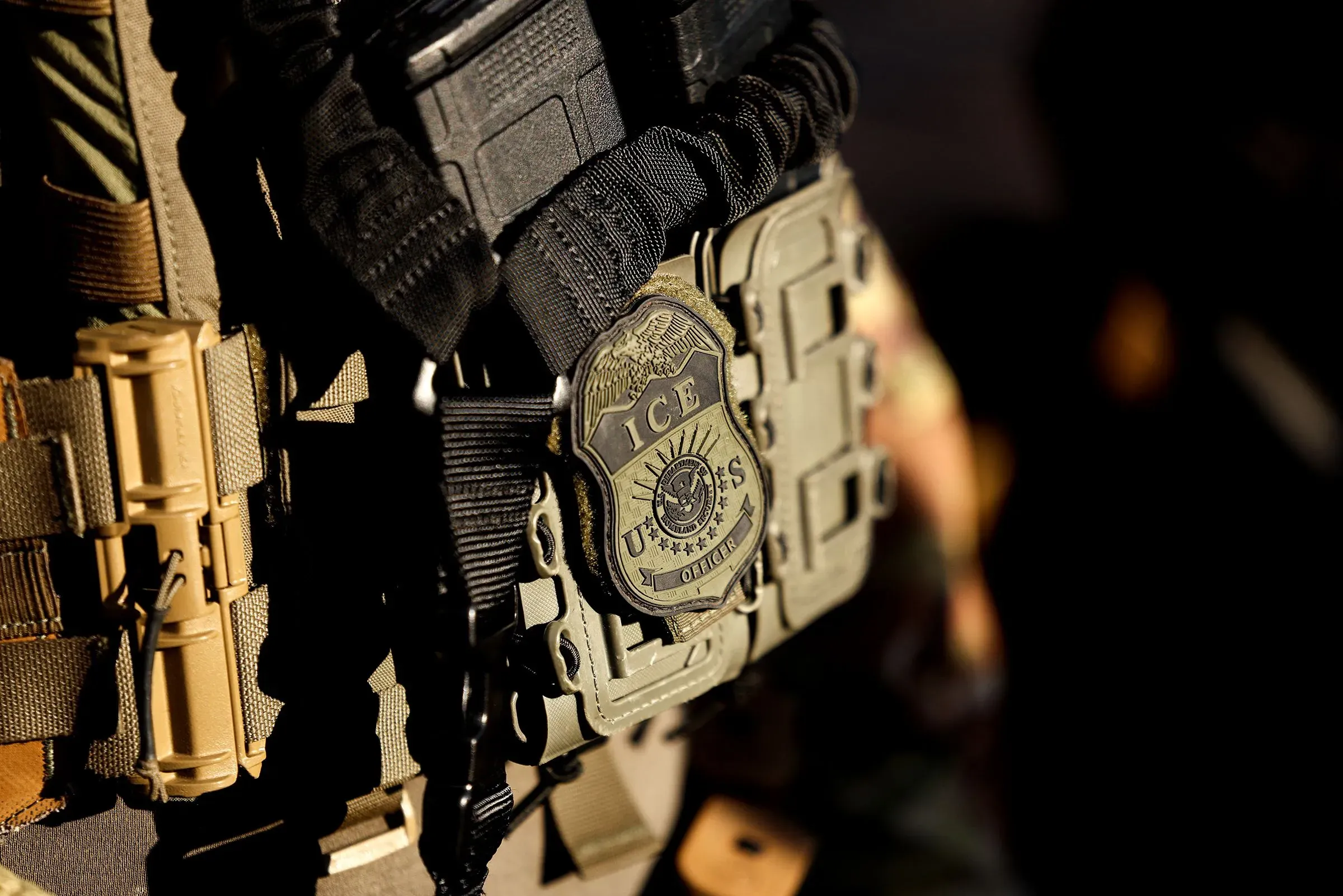 شعار وكالة إنفاذ قوانين الهجرة والجمارك مثبت على سترة أحد الضباط، مما يعكس الجدل حول استخدام القوة في عمليات الترحيل.