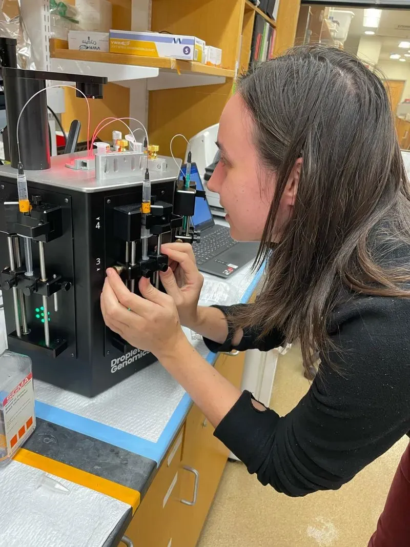 عالمة تعمل على جهاز مختبري متقدم لتحليل أجنة الضفادع، مما يعكس دورها الحيوي في الأبحاث المتعلقة بالكشف عن السرطان.