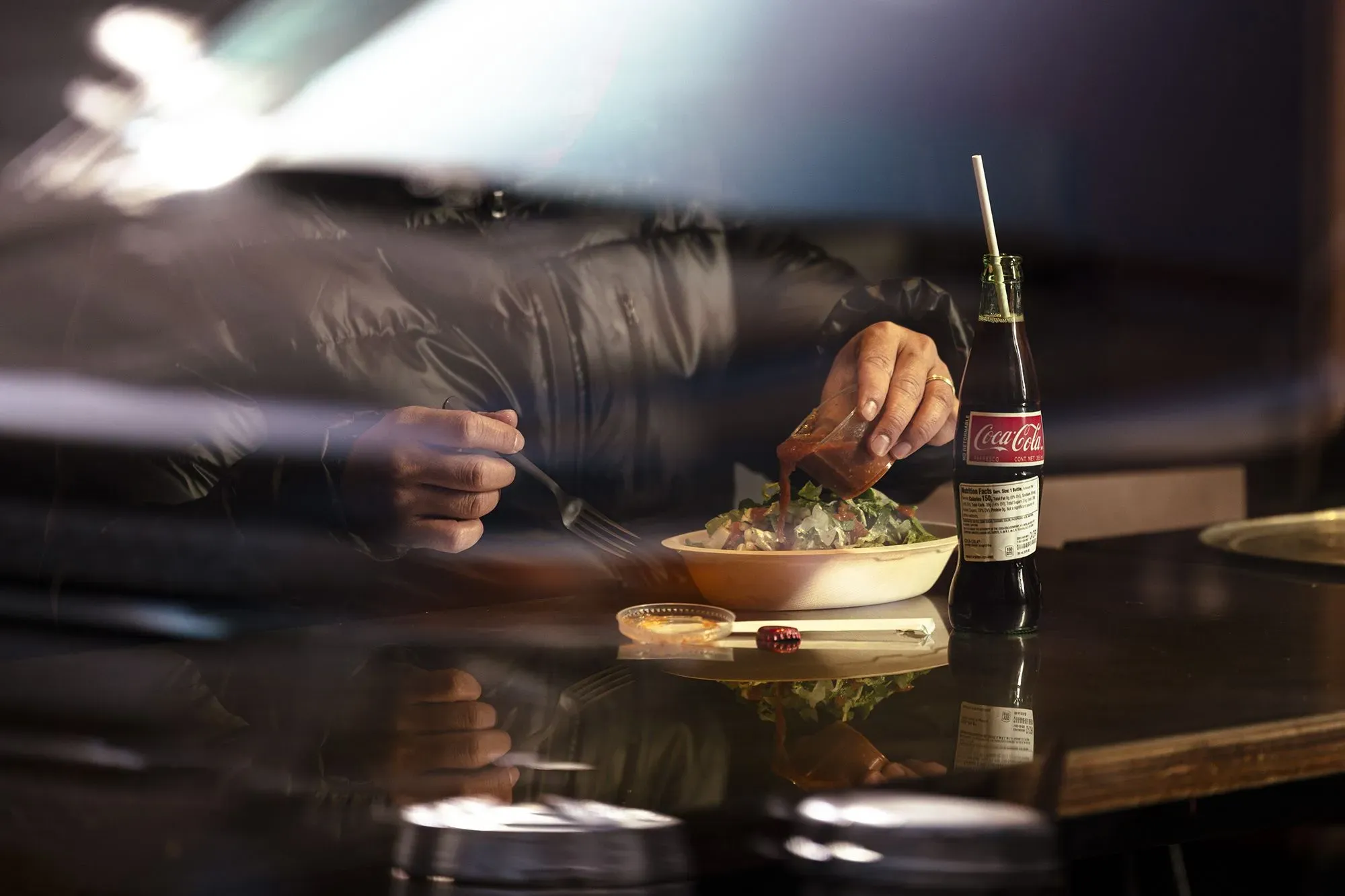 شخص يتناول وعاءً من السلطة مع مشروب غازي، يعكس اتجاهات تناول الطعام السريعة وتأثيرها على أرباح المطاعم.