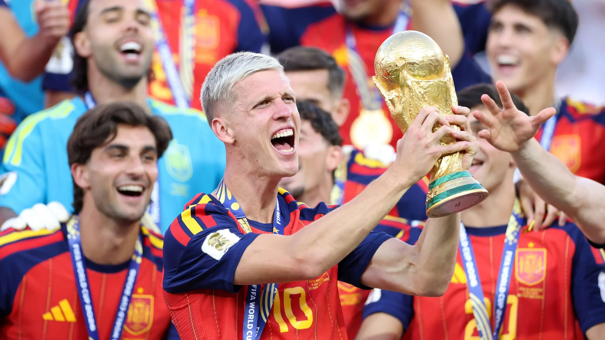 لاعبو منتخب إسبانيا يحتفلون بالفوز بكأس العالم، مع التركيز على لاعب يرفع الكأس وسط فرحة الفريق.