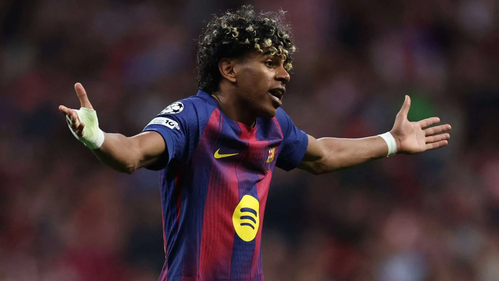 لاعب برشلونة لامين يمال يرفع ذراعيه بتعبير حائر خلال مباراة، مع التركيز على مستقبله الكروي بعد تحقيق ألقاب كبيرة في سن مبكرة.