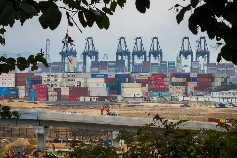 صورة لميناء يحتوي على حاويات شحن ملونة وأجهزة تحميل، تعكس تأثير التعريفات الجمركية على التجارة العالمية.