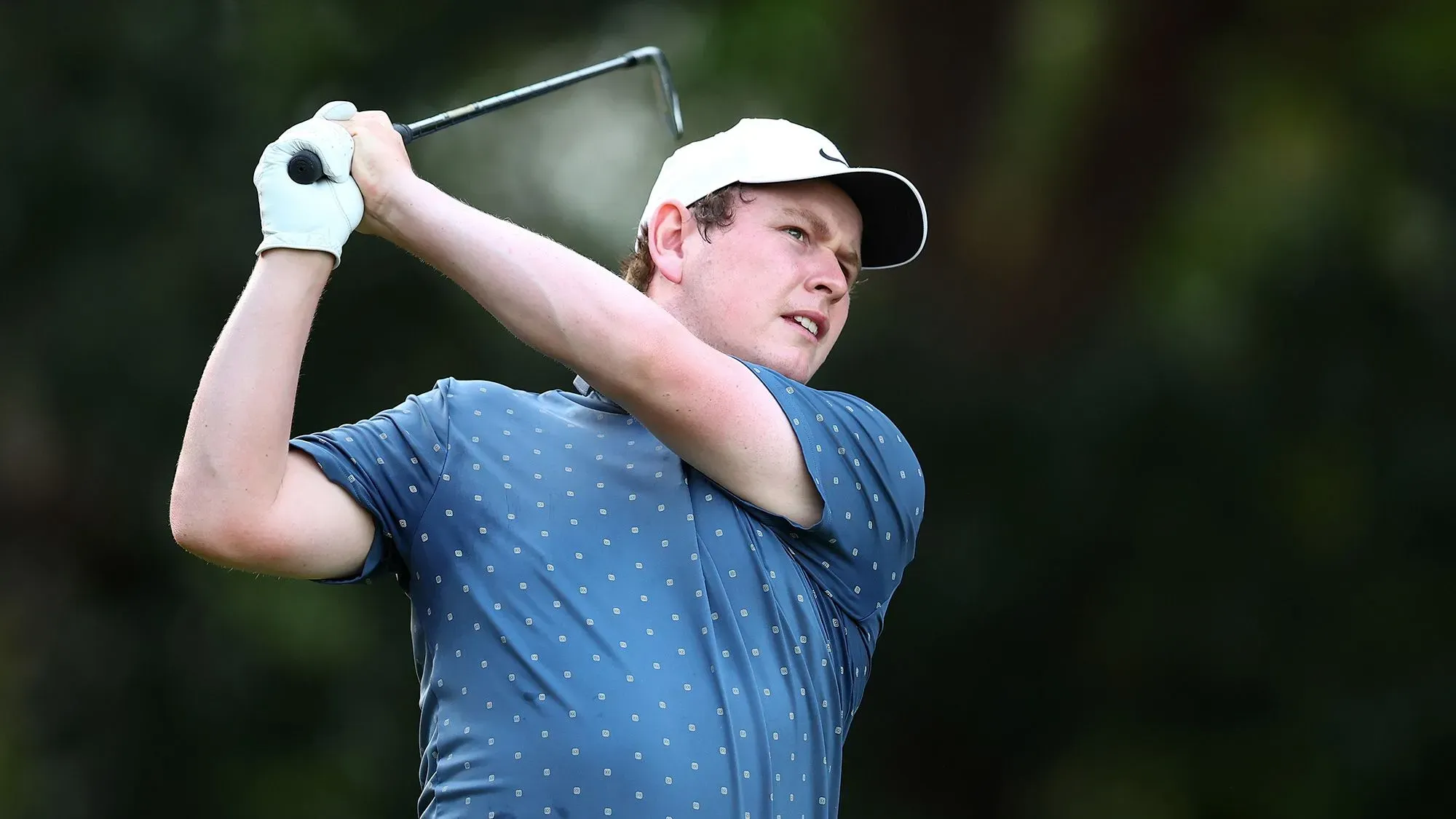 روبرت ماكينتاير، لاعب جولف شاب، يستعد لضربة في ملعب الجولف، مع التركيز على اللعبة وأجواء المنافسة.