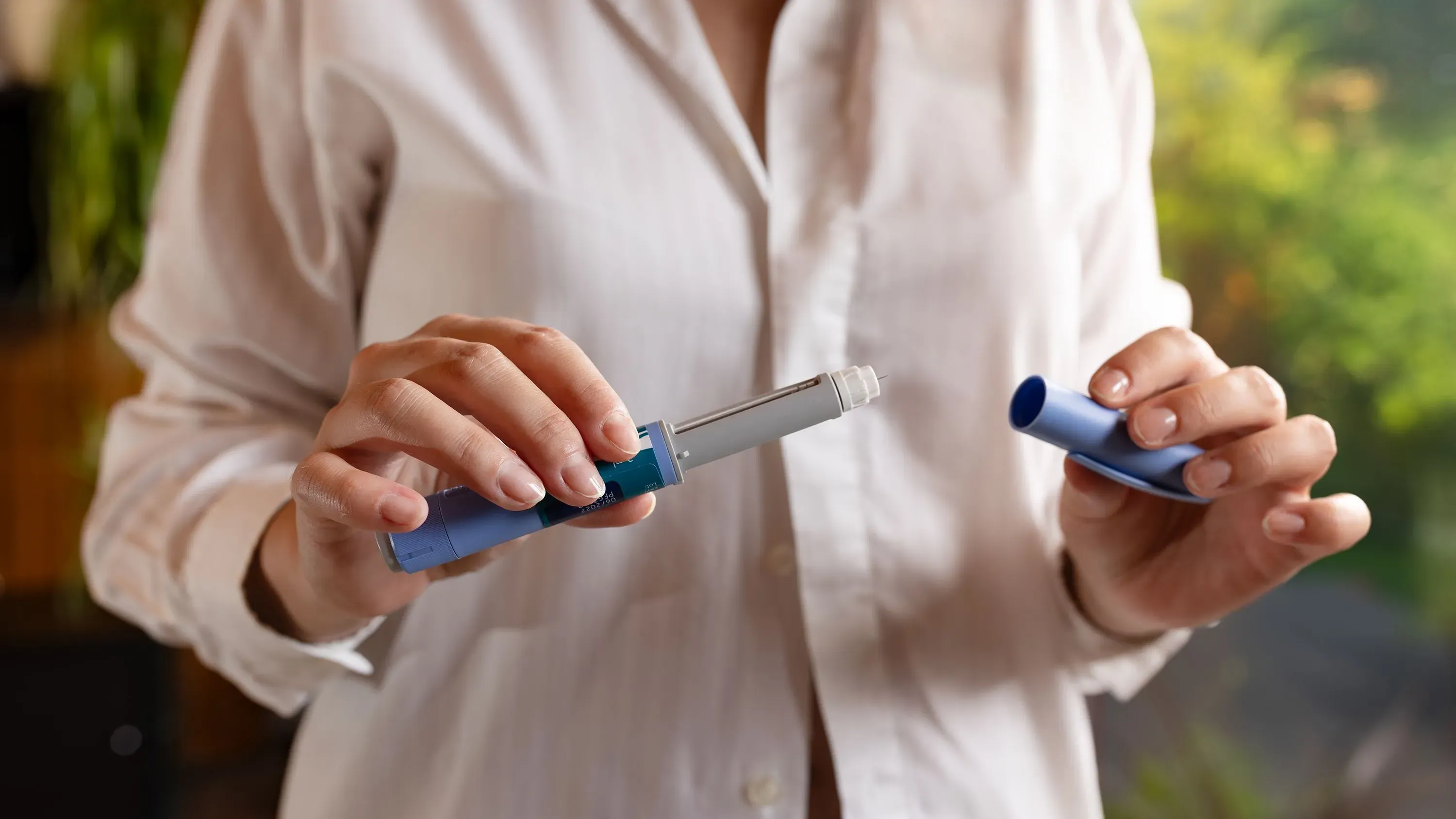 امرأة تحمل قلم حقن دواء GLP-1، مع التركيز على تفاصيل القلم، مما يعكس أهمية العلاج في تقليل مخاطر القلب.