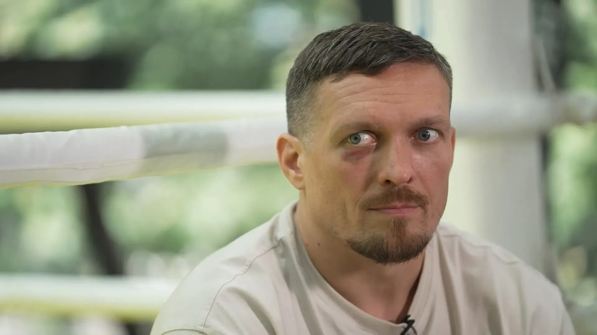 أوليكساندر أوسيك، بطل العالم في الملاكمة للوزن الثقيل، يظهر في صالة رياضية، مع نظرة جدية تعكس التحديات التي تواجه أوكرانيا.