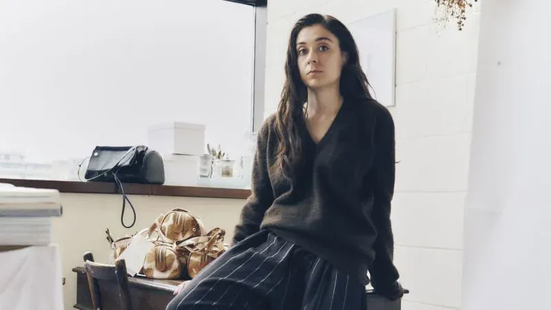 تاليا ليبكين-كونور، مصممة أزياء، تجلس في استوديوها شرق لندن، تعكس تراث عائلتها في مجال الموضة.