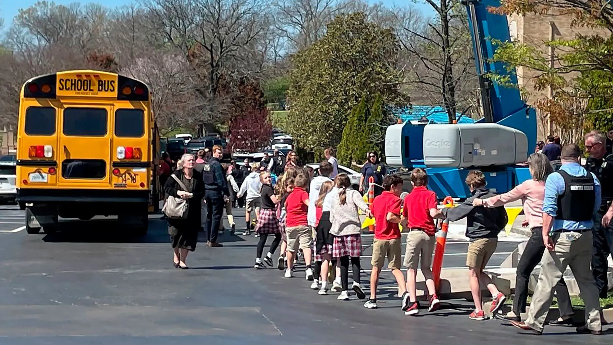 طلاب يتجهون نحو حافلة مدرسية بعد حادث إطلاق نار في مدرسة العهد بناشفيل، مع وجود رجال الشرطة في الموقع.