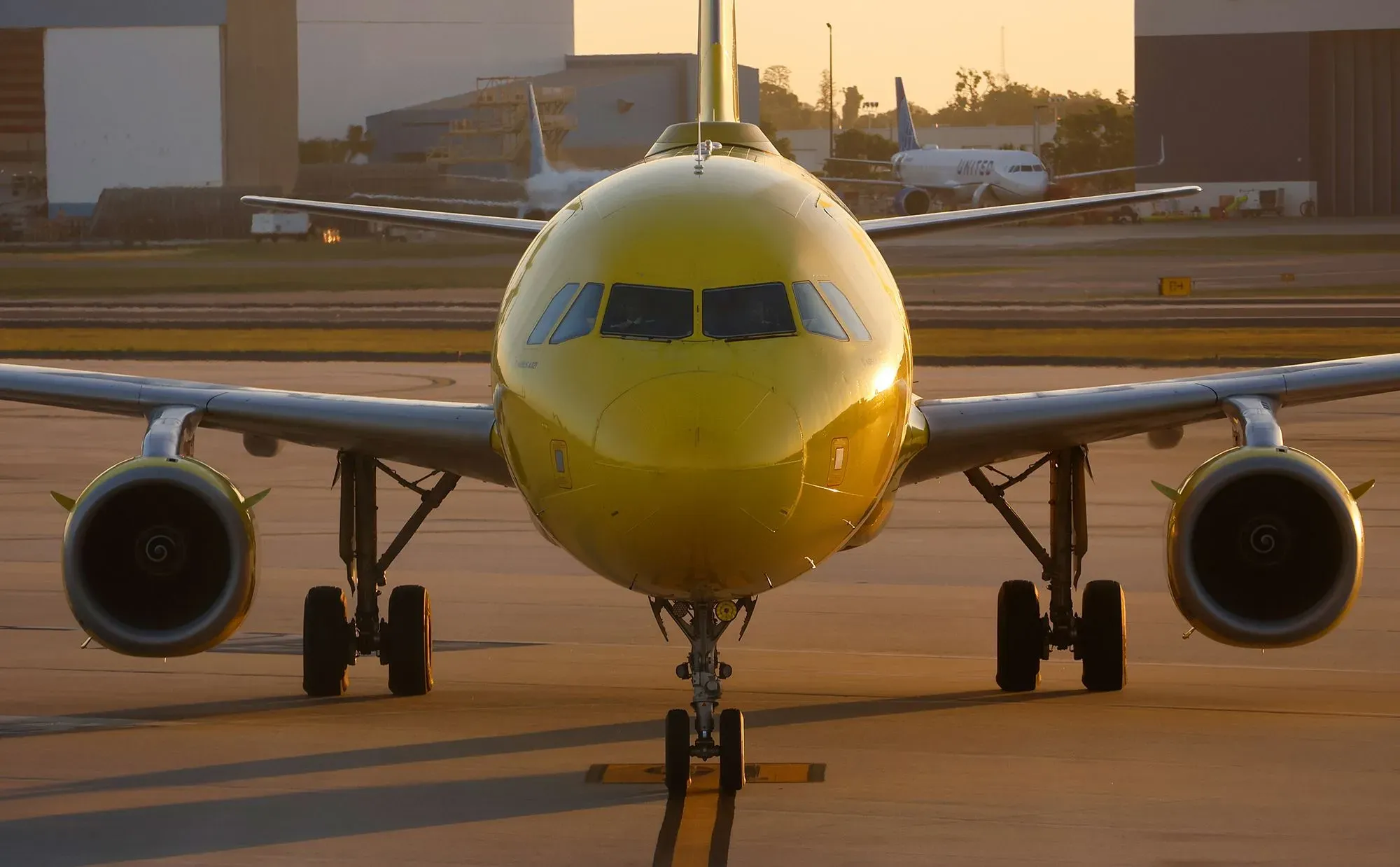 طائرة شركة سبيريت ذات اللون الأصفر تنتظر على مدرج المطار، مما يعكس التحديات التي تواجهها الشركة في ظل المخاوف من الإغلاق وارتفاع الأسعار.