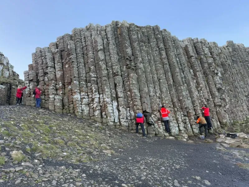 عمال يقومون بإزالة العملات المعدنية من أعمدة جسر العملاق في أيرلندا الشمالية، لحماية الموقع من الأضرار الناتجة عن التآكل.