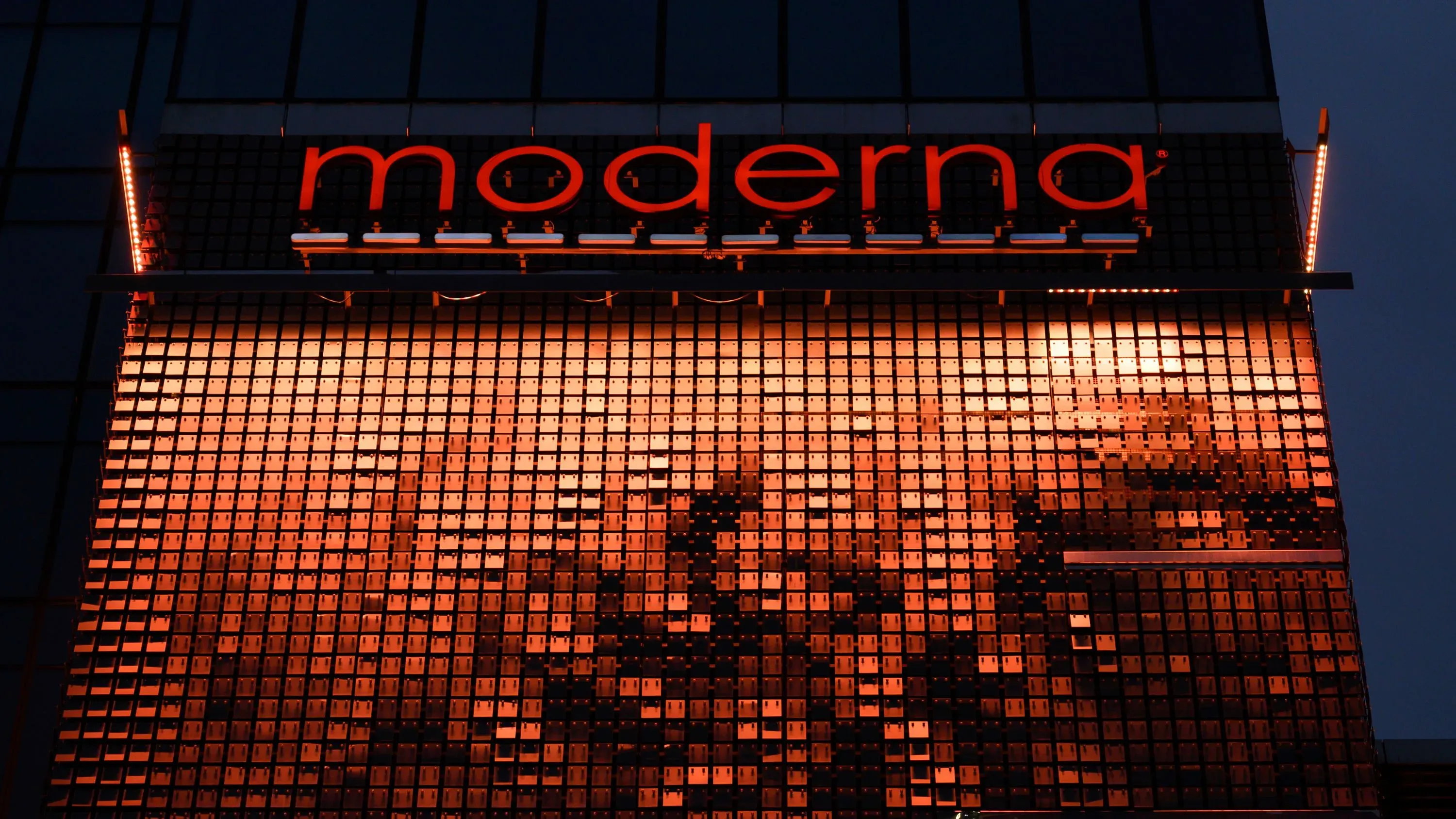 شعار شركة موديرنا مضيء على واجهة مبنى، يعكس التزام الشركة بتطوير لقاح ضد إنفلونزا الطيور.