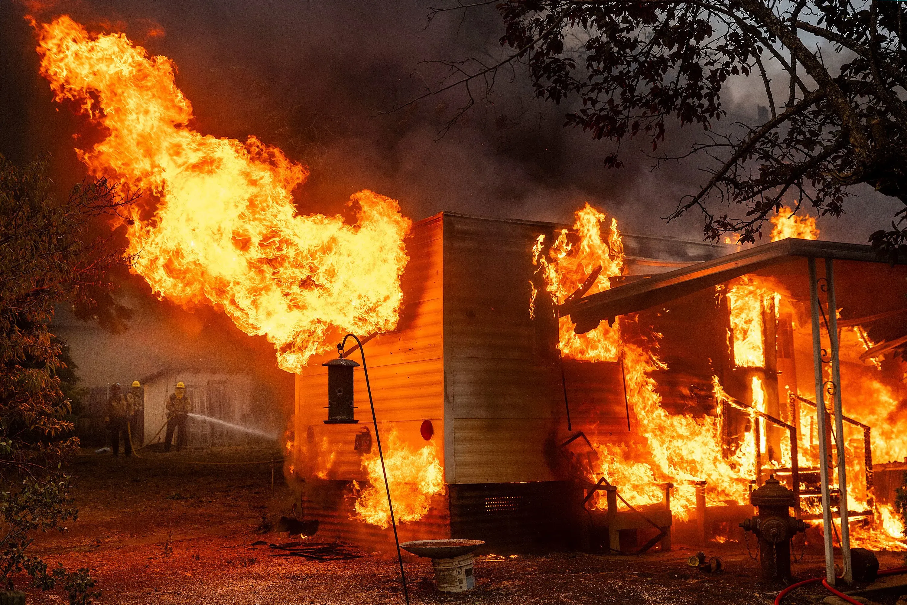 حريق هائل يلتهم منزلاً في بلدة تشاينا كامب بكاليفورنيا، مع جهود رجال الإطفاء لإخماده وسط ألسنة اللهب.