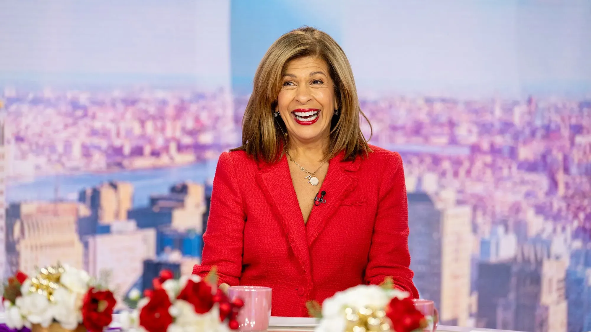 هدى قطب، المذيعة الشهيرة، تبتسم أثناء تقديم برنامج \"توداي\"، محاطة بأزهار ملونة، في يومها الأخير بالبرنامج.