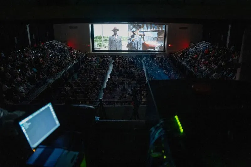 صالة سينما مزدحمة تعرض فيلمًا، مع جمهور متفاعل أمام الشاشة الكبيرة، مما يعكس انتعاش صناعة السينما بعد الجائحة.