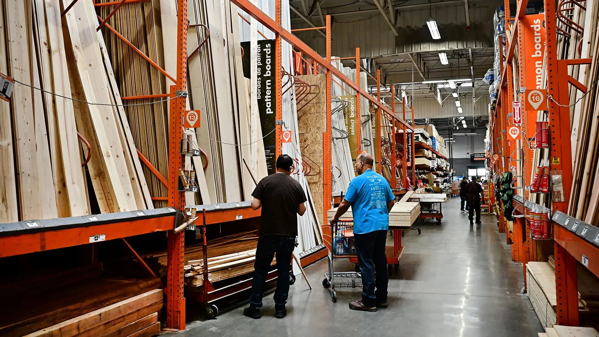 متسوقون في متجر هوم ديبوت، يتجولون بين رفوف الخشب والأدوات، مع التركيز على استقرار الأسعار وسط التحديات الاقتصادية.