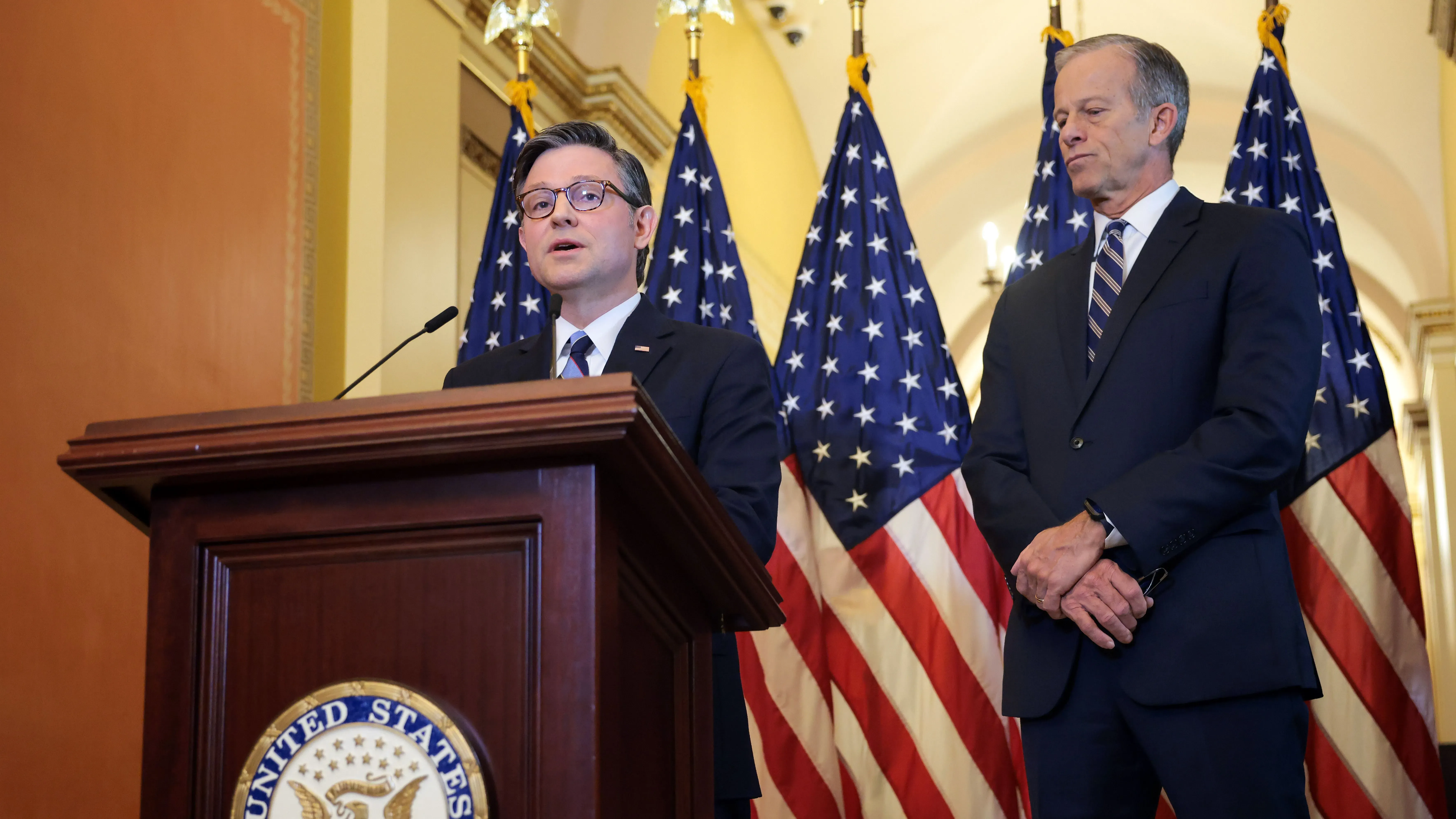 اجتماع بين رئيس مجلس النواب مايك جونسون وزعيم الأغلبية في مجلس الشيوخ جون ثون، مع أعلام الولايات المتحدة خلفهم، أثناء مناقشة تخفيضات الميزانية.