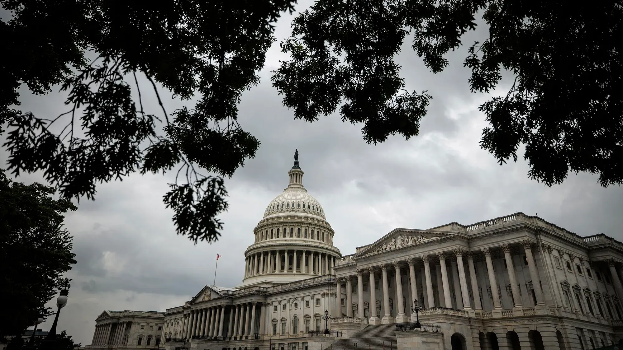 مبنى الكابيتول الأمريكي تحت سماء غائمة، مع أشجار تحيط به، مما يعكس التحديات الأمنية للمشرعين في ضوء التهديدات المتزايدة.