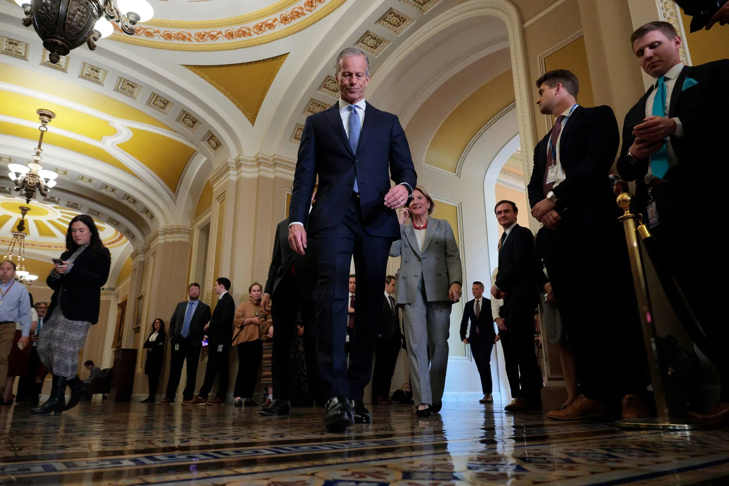 مجموعة من أعضاء مجلس النواب تسير في ممر الكابيتول، مع التركيز على زعيم الأغلبية جون ثون، بعد تصويت لإلغاء بند قانوني مثير للجدل.