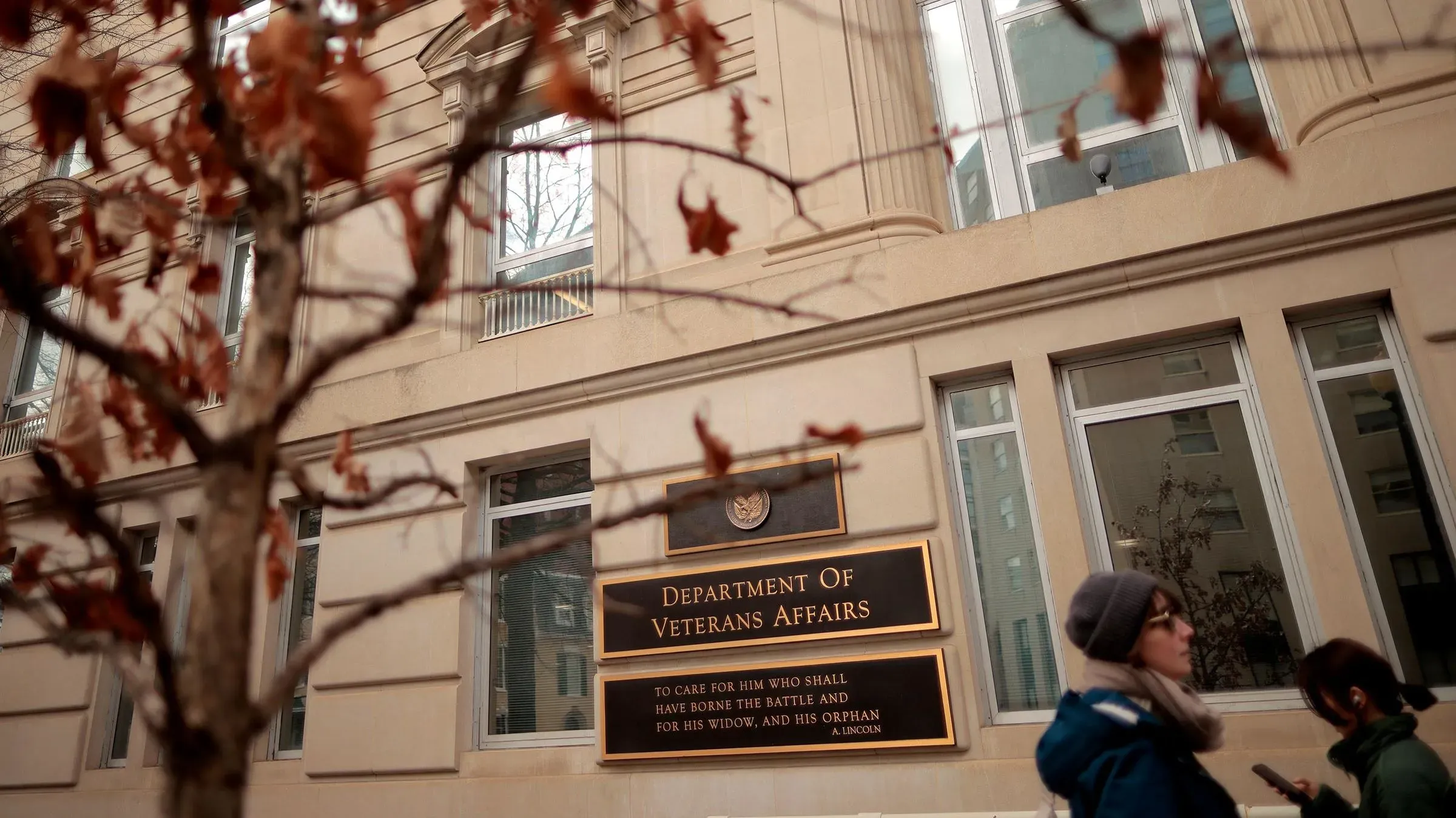 مبنى وزارة شؤون المحاربين القدامى يظهر في الصورة، مع أشخاص يسيرون بجواره، مما يعكس التحديات المتعلقة بالإسكان للمحاربين القدامى.