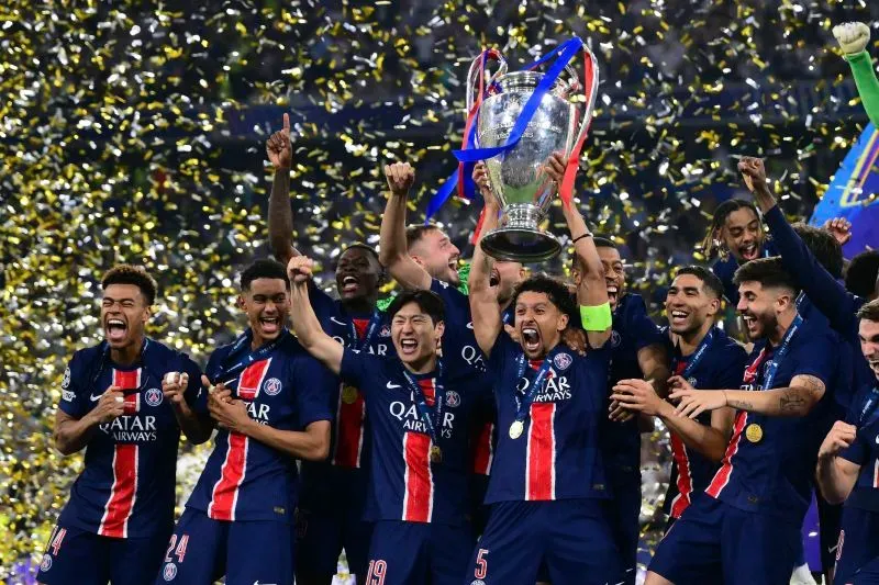 فريق باريس سان جيرمان يحتفل بفوزه بدوري أبطال أوروبا، حيث يرفع اللاعبون الكأس وسط أجواء من الفرح والاحتفالات والألعاب النارية.