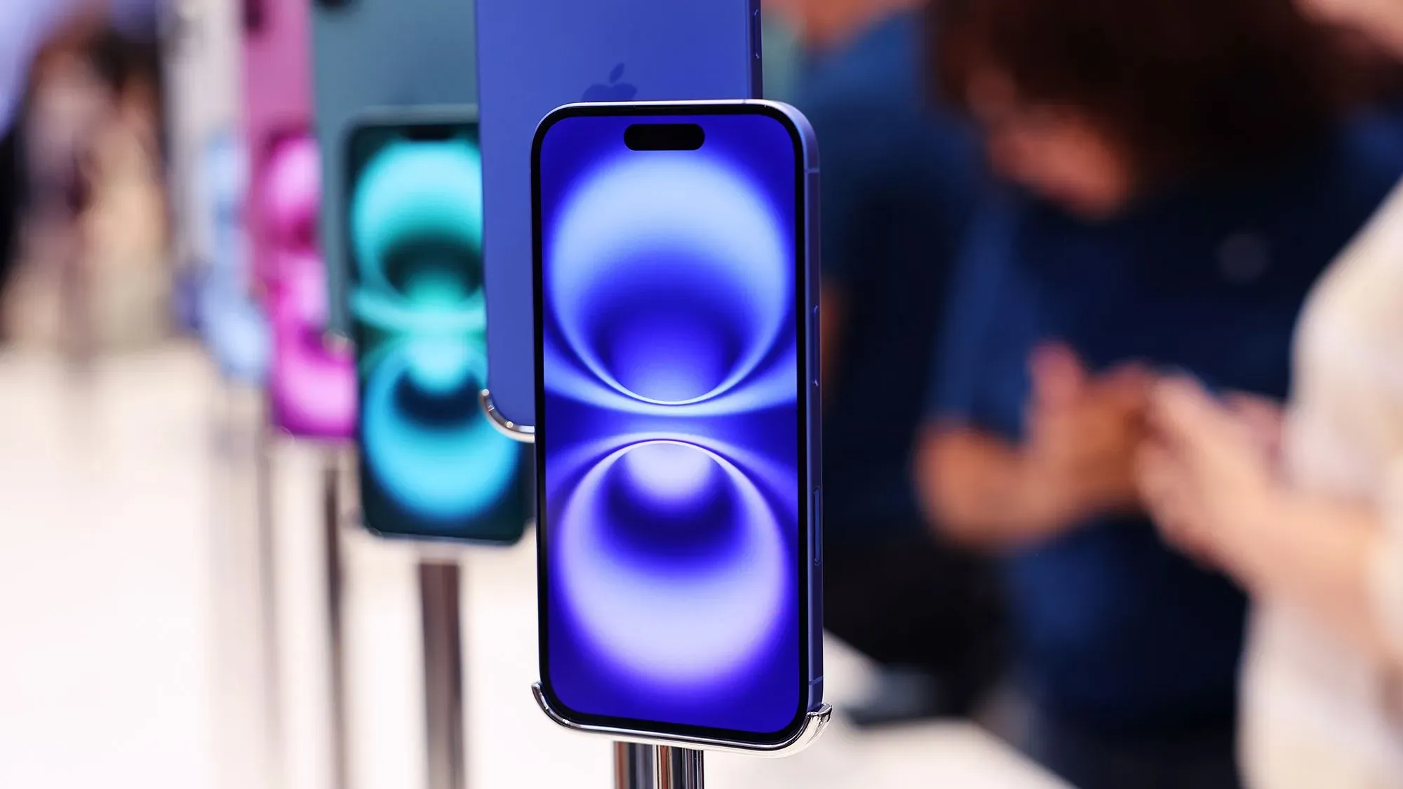 عرض لجهاز iPhone جديد بألوان متنوعة، مع التركيز على الشاشة ذات التصميم العصري. يُظهر التوجه نحو الابتكار والتكنولوجيا الحديثة في الأجهزة الذكية.