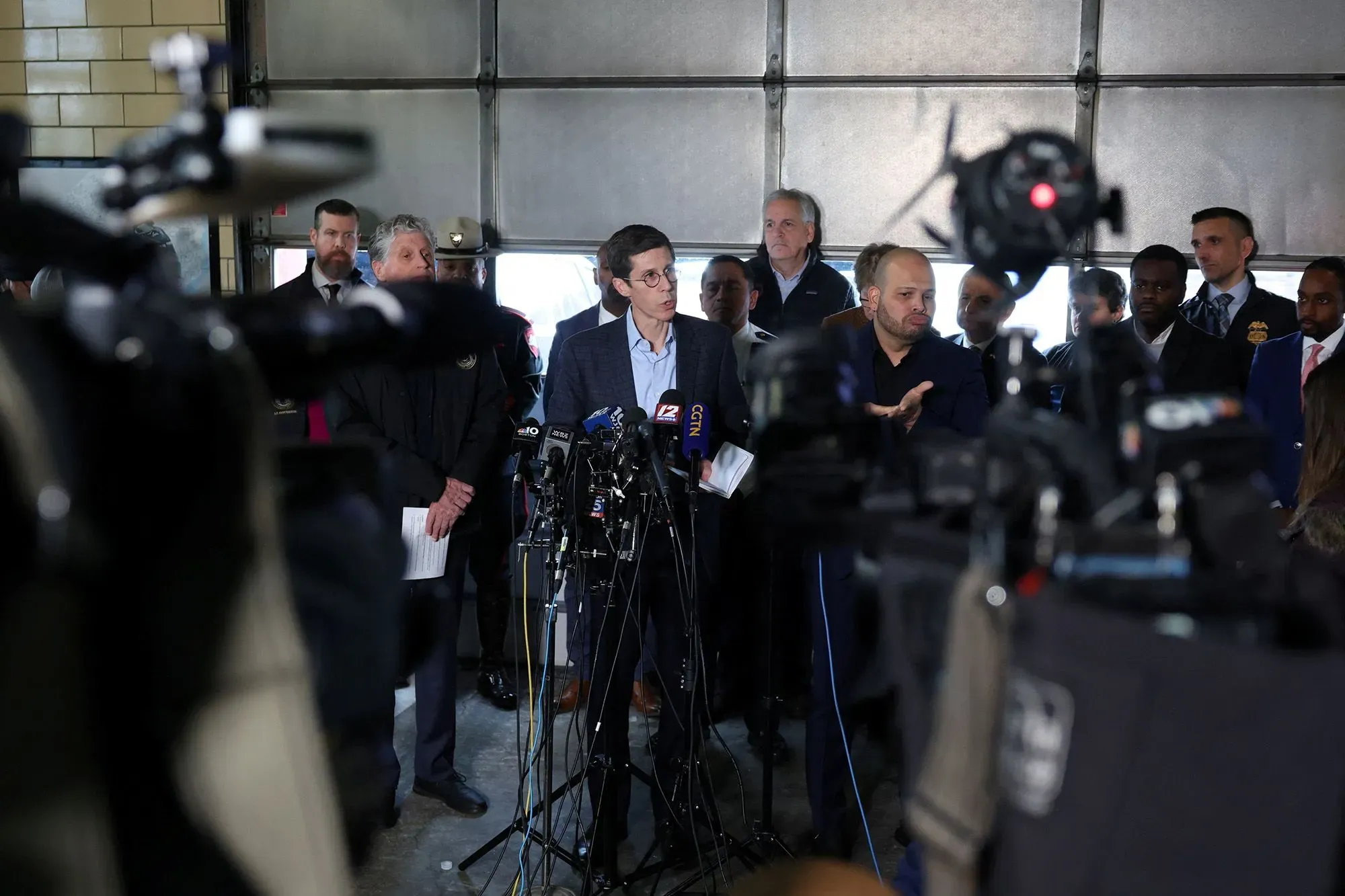 عمدة بروفيدنس بريت سمايلي يتحدث أمام الصحافة بعد إطلاق النار في جامعة براون، مع وجود مسؤولين آخرين في الخلفية.