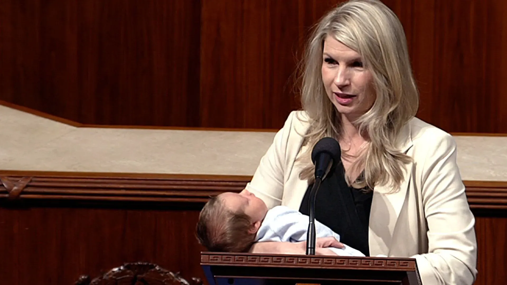 النائبة بريتاني بيترسن تحمل طفلها سام أثناء التصويت في مجلس النواب، مما يعكس تحديات الأمهات الجدد في السياسة.