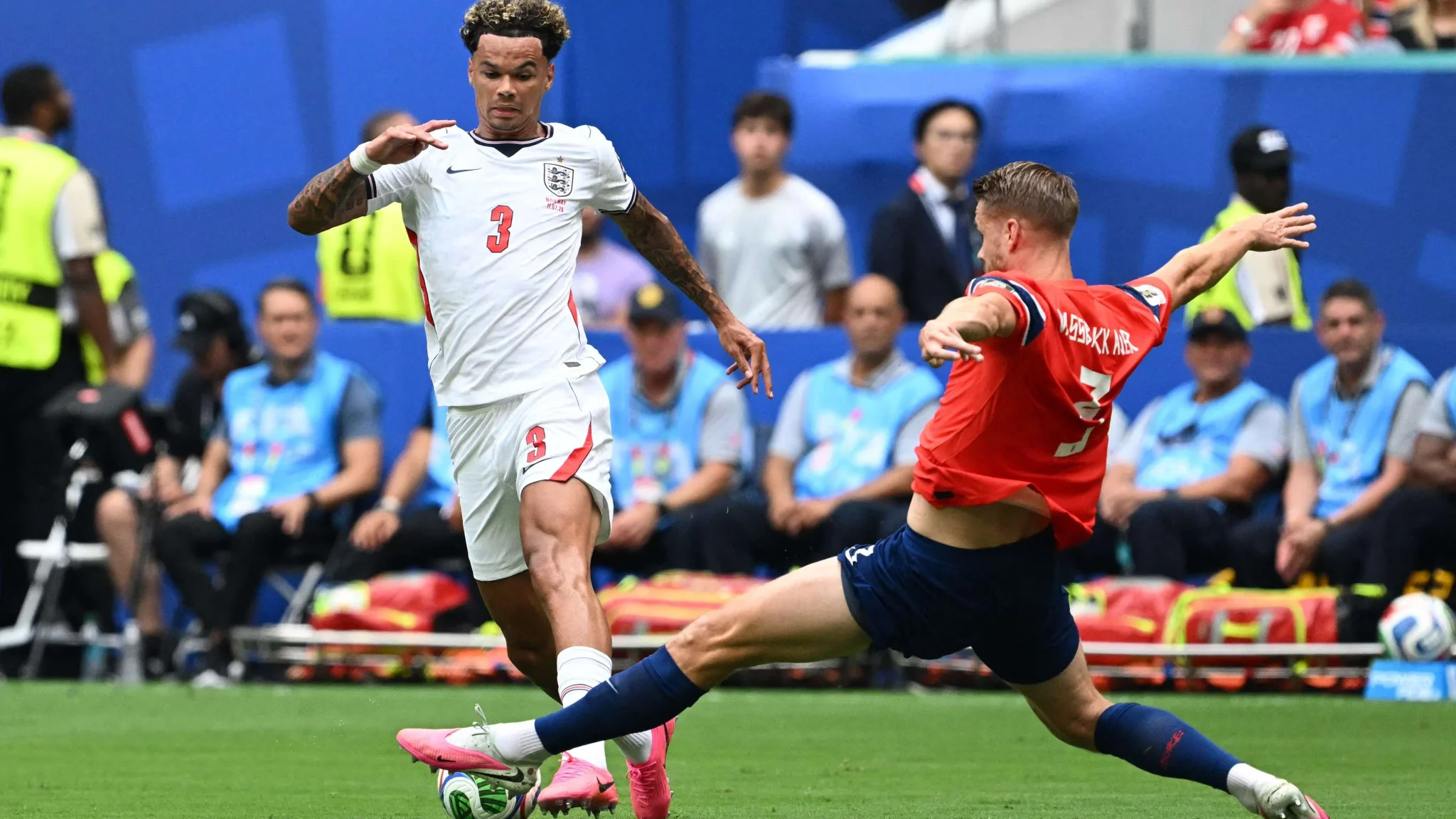 لاعب إنجليزي يرتدي الرقم 3 ينفذ تدخلًا دفاعيًا ضد لاعب أرجنتيني في مباراة كرة قدم ضمن نصف نهائي كأس العالم، مع تركيز على التنافس والتكتيك الدفاعي.