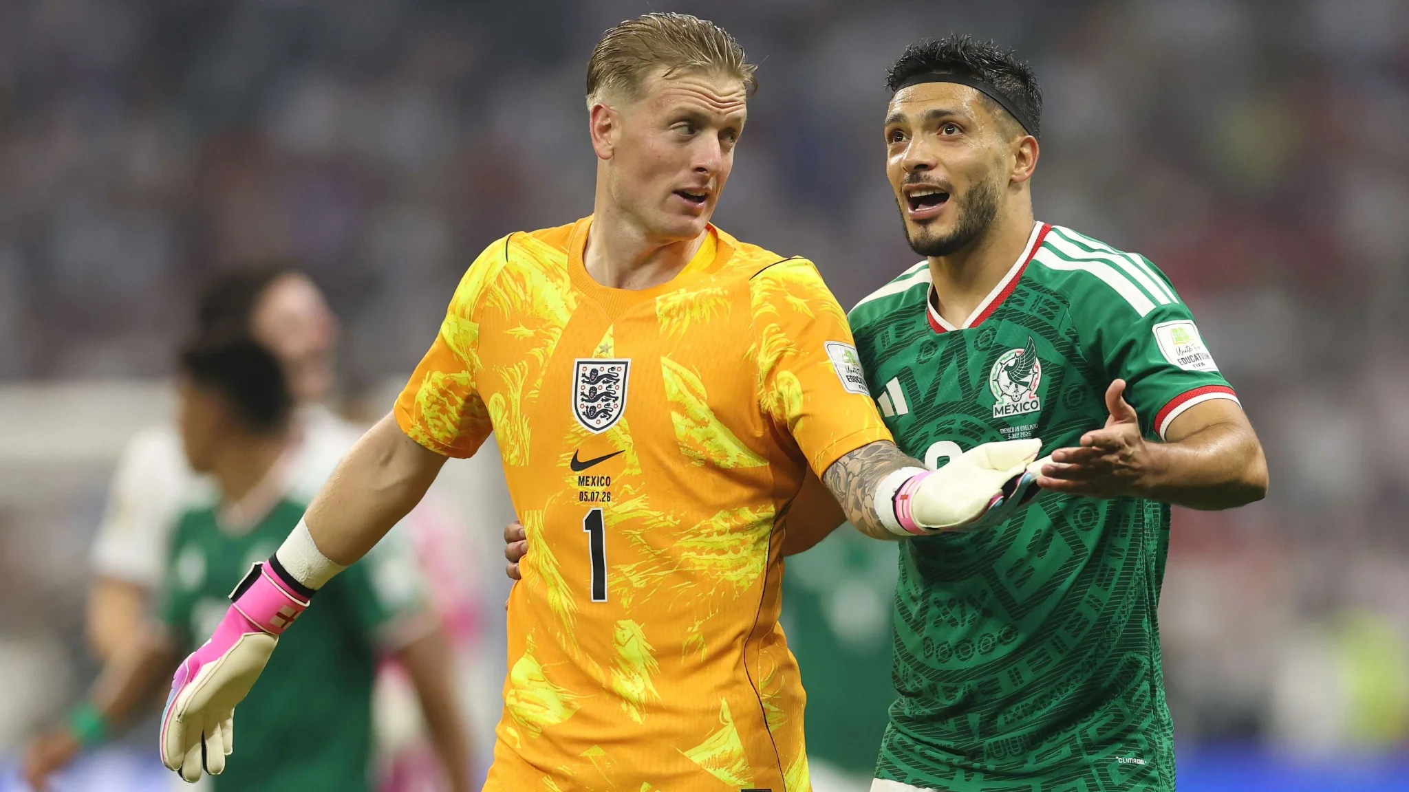 حارس إنجلترا جوردان بيكفورد يرتدي الزي البرتقالي يتحدث مع لاعب المكسيك خلال مباراة كأس العالم 2026.