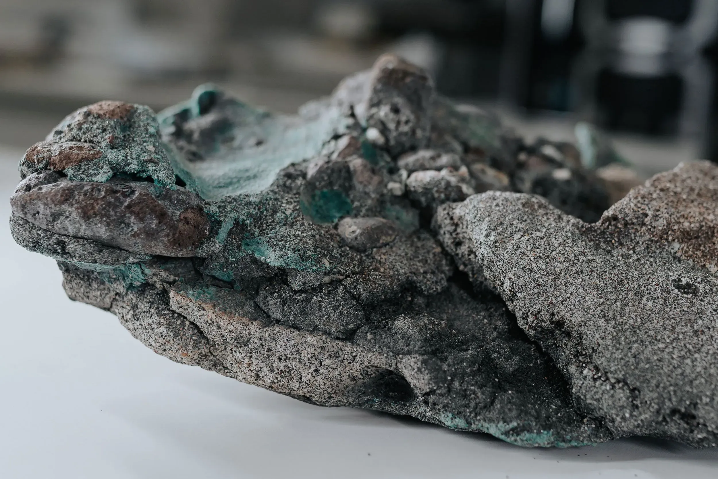 صخرة بلاستيكية مختلطة مع مواد طبيعية، تظهر آثار تآكل وتغيرات كيميائية نتيجة التلوث البلاستيكي.